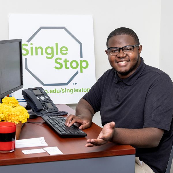 A student sits at a desk with a "Single Stop" sign in the background