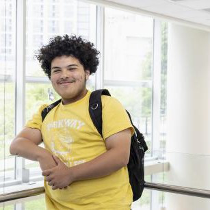 A student posing in front of a glass-enclosed atrium