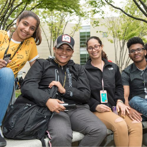 Four students sit in a courtyard at the Community College of Philadelphia