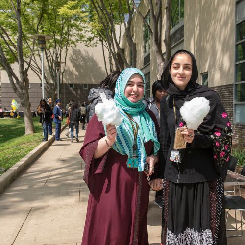 Two students with cotton candy standing outside a building on the Community College of Philadelphia campus